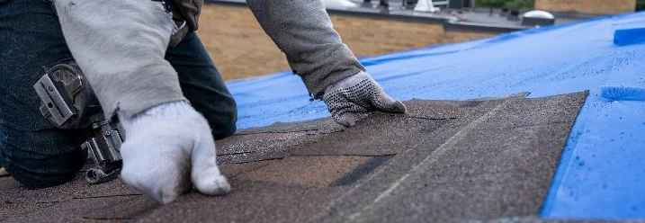 Person befestigt Dachpappe auf Dach